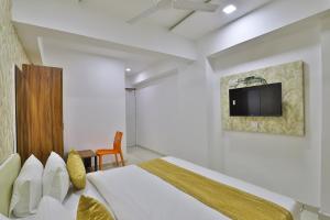 a bedroom with a bed and a tv on the wall at HOTEL SHALIGRAM in Ahmedabad