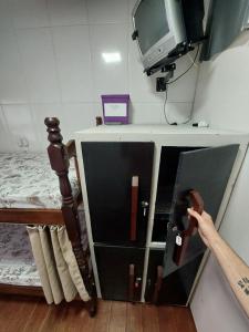 una persona abriendo un cajón en una habitación con TV en Pousada Rancho 60, en Balneário Camboriú