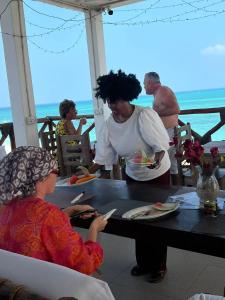 een vrouw aan een tafel met een bord eten bij Kassandra Beach Hotel in Nungwi