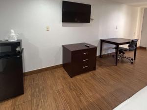 Habitación con escritorio, TV y mesa. en Motel 6 Denham Springs, LA, en Denham Springs