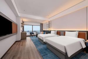 a hotel room with two beds and a flat screen tv at Wyndham Putian Downtown in Putian