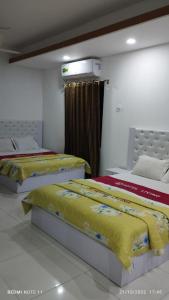 2 camas en una habitación con sábanas amarillas y rojas en Hotel living international ltd. en Dhaka