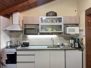 una cocina con armarios blancos y fregadero en Anita Haus Casa de fin de semana en Garupá