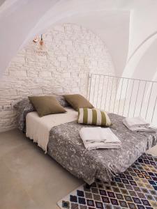 Bett in einem Zimmer mit einer weißen Ziegelwand in der Unterkunft SamSaraHouse Salento in Felline