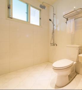 a white bathroom with a toilet and a window at Tang Chao B&B in Jiaoxi