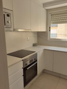 uma cozinha com armários brancos e um forno com placa de fogão em PAAL PLAYA Solo Familias em Playa de Gandia