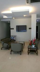a waiting room with couches and a tv on a wall at The Corum View Hotel in Bayan Lepas