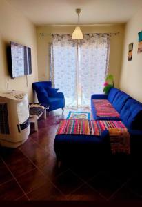 Porto Matroh New Chalets في مرسى مطروح: غرفة معيشة مع أريكة زرقاء وتلفزيون