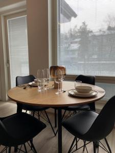 una mesa de madera con sillas, platos y copas de vino en High-ceilinged apartment with balcony en Tampere