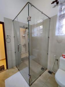 a glass shower in a bathroom with a toilet at Siroma Villa in Bentota