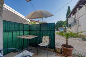 une table, une chaise et un parasol sur une clôture dans l'établissement Apartment in Porec - Istrien 46934, à Poreč