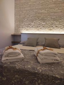 ein Bett mit zwei Kissen und einer Ziegelwand in der Unterkunft SamSaraHouse Salento in Felline