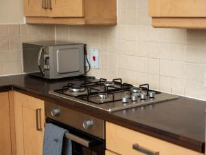encimera de cocina con fogones y microondas en Luxury 2 Bed Apartment – Near Heathrow, Legoland, Windsor Slough, en Slough