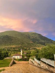 a village with a church and a mountain at LURA Hotel in Peshkopi