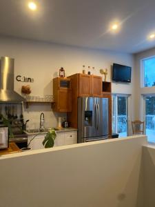 a kitchen with a stainless steel refrigerator and wooden cabinets at Le Monk ,chalet, motoneige, quad ,nature, randonné pédestre in Montmagny