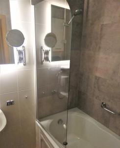 a bathroom with a shower and a tub and a sink at Landhotel Waldschlößchen in Sohland