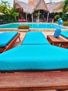 a swimming pool with blue cushioned tables and benches at Hotel de Charme Castelinho in Canoa Quebrada