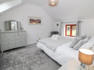 a white bedroom with a bed and a dresser at Croft Cottage in Castleton