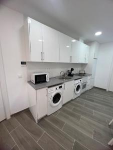 a kitchen with white cabinets and a sink and washing machines at Apartamentos BEACHYDAYS Metropolis D in Torremolinos +6 photos