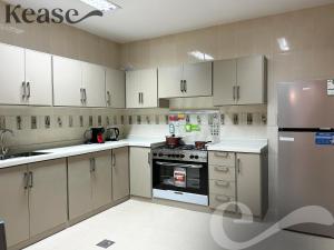 a kitchen with white cabinets and a stove and refrigerator at Kease Al-Mutamarat A-8 Timeless History GZ29 in Riyadh