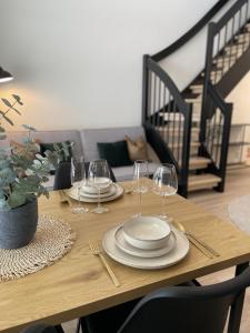 a wooden table with plates and wine glasses on it at Bright loft apartment with glazed balcony in Tampere