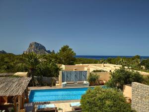 a resort with a swimming pool and mountains in the background at Cozy three bedroom villa with Es Vedra views! in Cala Vadella