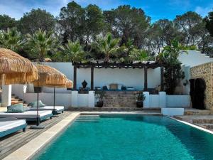 een zwembad met stoelen en een parasol naast een huis bij Beautiful villa for 12 people in San Jose de sa Talaia
