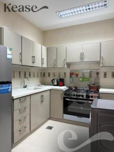 a kitchen with white cabinets and a black appliance at Kease Al-Mutamarat A-5 Timeless History AG76 in Riyadh