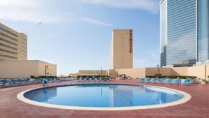 a large swimming pool with chairs and buildings at Modern 2BR 3BA Condo on the Boardwalk by CozySuites in Atlantic City