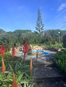 a swimming pool in a garden with red flowers at Alto da Praia Villa in Colares