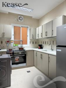 a kitchen with white cabinets and a sink and a refrigerator at Kease Al-Mutamarat A-3 Timeless History GX37 in Riyadh