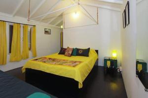 Art village resort Goa في محطة كاناكونا: غرفة نوم بسرير وبطانية صفراء