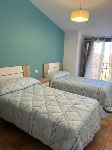 - 2 lits dans une chambre aux murs bleus dans l'établissement Casa Rural - Vivienda Arado, 