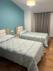 2 camas en una habitación con paredes azules en Casa Rural - Vivienda Arado, 