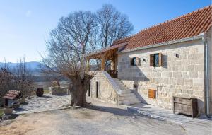 a stone building with a tree in front of it at 2 Bedroom Amazing Home In Obrovac Sinjski in Obrovac Sinjski