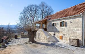 een stenen gebouw met een boom ervoor bij 2 Bedroom Amazing Home In Obrovac Sinjski in Obrovac Sinjski