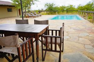 a wooden table and chairs next to a swimming pool at Mapesu Wilderness Tented Camp in Musina