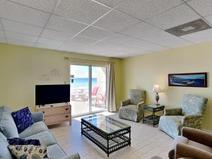 ein Wohnzimmer mit einem Sofa, Stühlen und einem TV in der Unterkunft Carefree 108 in Pensacola Beach