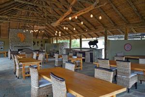 a restaurant with wooden tables and chairs and a bear on the wall at Mapesu Wilderness Tented Camp in Musina