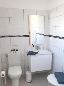 La salle de bains blanche est pourvue de toilettes et d'un lavabo. dans l'établissement Maison jardin privatif au coeur d'une oliveraie, à Roquevaire