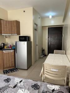 a small kitchen with a refrigerator and a table at Studio near Ayala Vertis North in Manila