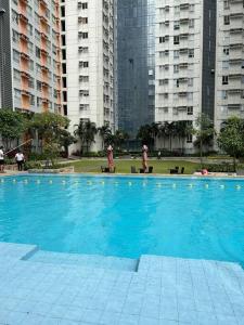 a large blue swimming pool in a city with tall buildings at Studio near Ayala Vertis North in Manila