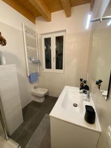 a white bathroom with a sink and a toilet at Appartamento in Valpolicella (AquardensGardaVerona in Settimo