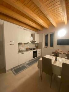 uma cozinha com armários brancos e uma mesa com cadeiras em Appartamento in Valpolicella (AquardensGardaVerona em Settimo