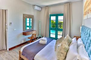 a bedroom with a bed and a desk and a window at 10 AKROTIRI, SANTORINI ESTATE - Families only in Ballito +44 photos