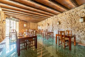 HOTEL EL CASTELL في فالديروبريس: مطعم بطاولات وكراسي خشبية وجدار حجري