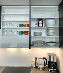 a kitchen cabinet filled with dishes and a coffee maker at Spacious loft apartment with Lake Näsijärvi views in Tampere