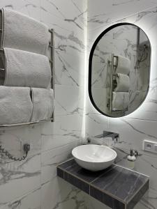 ein Badezimmer mit einem Waschbecken, einem Spiegel und Handtüchern in der Unterkunft Квартира на Огієнка 15 in Lwiw