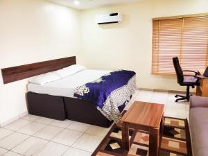 Central District Apartment (Abuja) في Aso: غرفة نوم بسرير وطاولة وكرسي