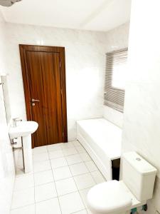 a white bathroom with a toilet and a sink at Central District Apartment (Abuja) in Aso